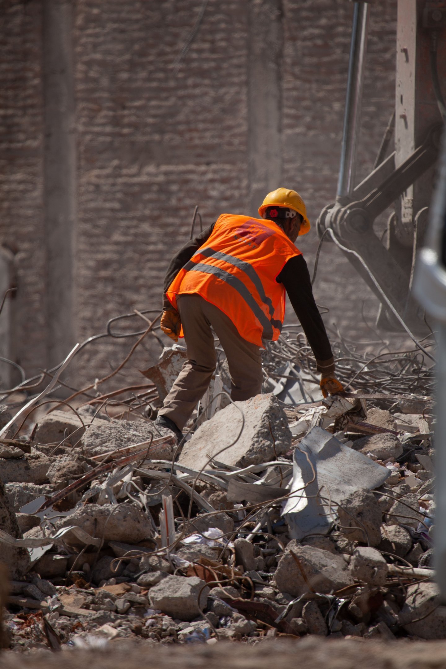 Worker in a hard hat and high-visibility vest clearing debris on a demolition site