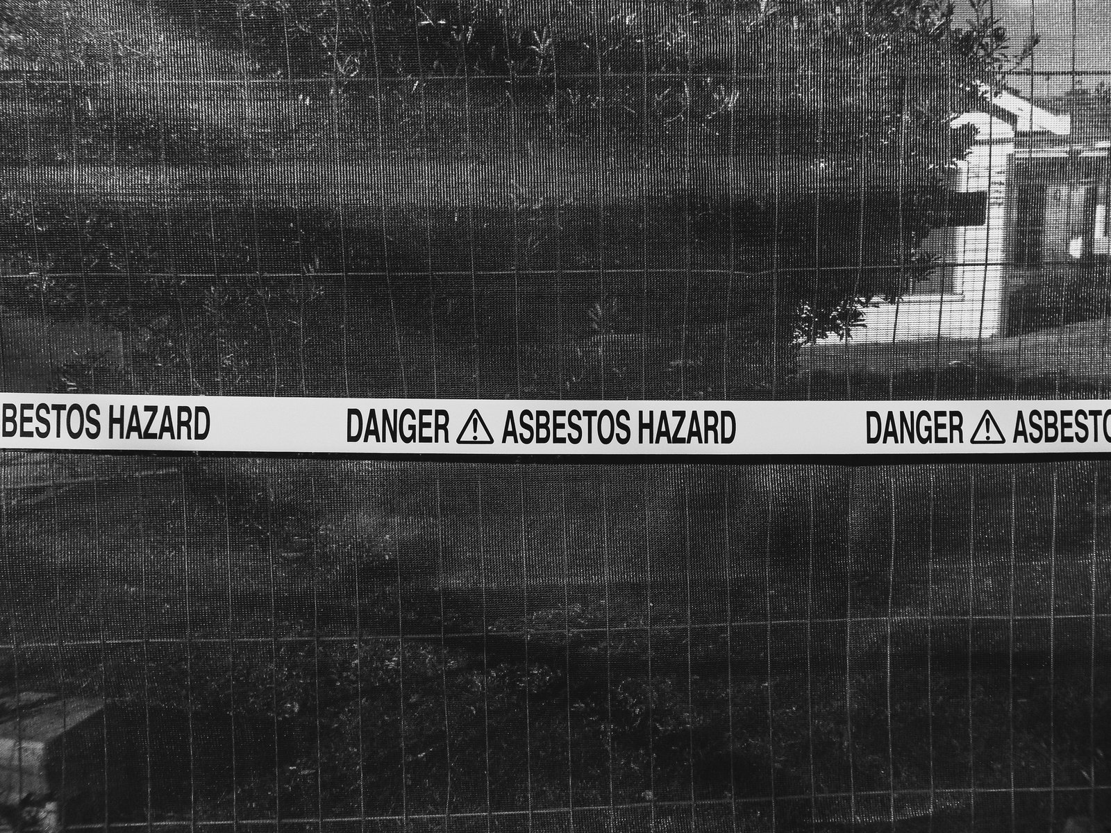Asbestos hazard warning tape across a site fence